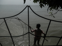 A boy is trying to catch fish from his washed-off house due to flood water in Kurigram, Bangladesh, on July 8, 2024. (