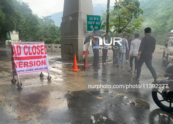 A road closed poster is being placed by the administration as workers are using excavators to clear a landslide along National Highway 10 th...