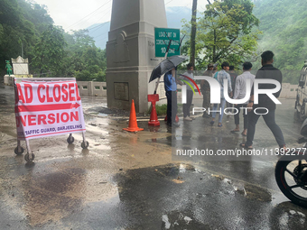 A road closed poster is being placed by the administration as workers are using excavators to clear a landslide along National Highway 10 th...