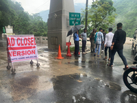 A road closed poster is being placed by the administration as workers are using excavators to clear a landslide along National Highway 10 th...