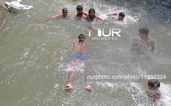 Boys are cooling themselves off on a hot summer day on the outskirts of Srinagar, Kashmir, on July 08, 2024. According to the weather depart...