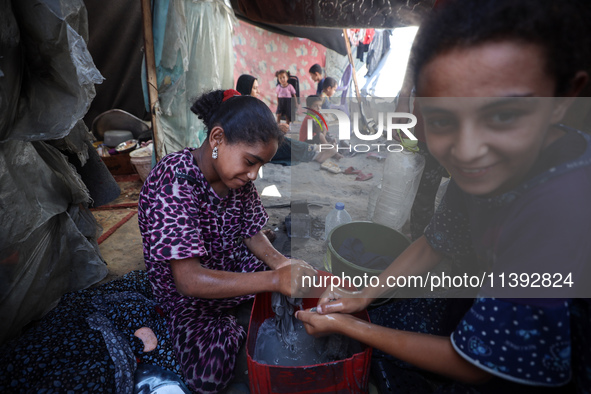 Displaced Palestinian girls are hand-washing clothes with a bar of soap at their displacement tent in Deir el-Balah in the central Gaza Stri...