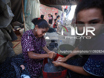 Displaced Palestinian girls are hand-washing clothes with a bar of soap at their displacement tent in Deir el-Balah in the central Gaza Stri...