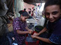 Displaced Palestinian girls are hand-washing clothes with a bar of soap at their displacement tent in Deir el-Balah in the central Gaza Stri...