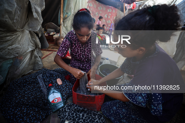 Displaced Palestinian girls are hand-washing clothes with a bar of soap at their displacement tent in Deir el-Balah in the central Gaza Stri...