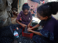 Displaced Palestinian girls are hand-washing clothes with a bar of soap at their displacement tent in Deir el-Balah in the central Gaza Stri...