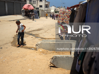 A girl is pulling a cart of water containers past a line of displacement tents in Deir el-Balah, Gaza Strip, on July 8, 2024, amid the ongoi...