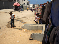 A girl is pulling a cart of water containers past a line of displacement tents in Deir el-Balah, Gaza Strip, on July 8, 2024, amid the ongoi...