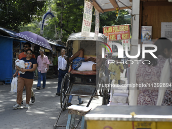 A rickshaw puller is relaxing on his rickshaw during the afternoon, in North Kolkata, India, on July 8, 2024. (