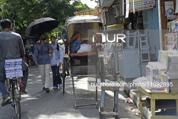 A rickshaw puller is relaxing on his rickshaw during the afternoon, in North Kolkata, India, on July 8, 2024. 