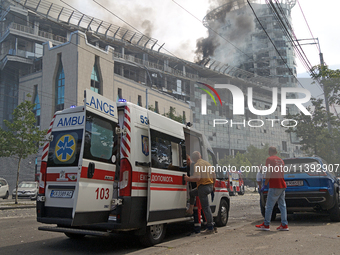 An ambulance is parking near the Lukianivska metro station as smoke is rising over an unfinished building during a Russian missile attack in...