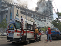 An ambulance is parking near the Lukianivska metro station as smoke is rising over an unfinished building during a Russian missile attack in...