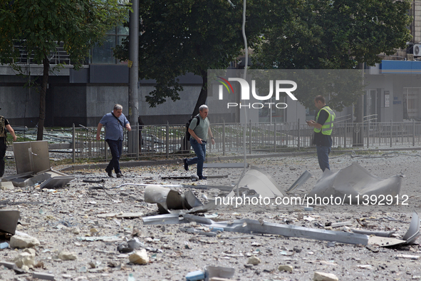 A police officer and men are crossing a street covered with rubble near the Lukianivska metro station during a Russian missile attack in Kyi...