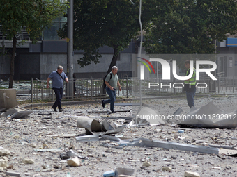 A police officer and men are crossing a street covered with rubble near the Lukianivska metro station during a Russian missile attack in Kyi...