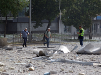 A police officer and men are crossing a street covered with rubble near the Lukianivska metro station during a Russian missile attack in Kyi...