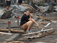 A young man is sitting on the curb among the debris near the Lukianivska metro station during a Russian missile attack in Kyiv, Ukraine, on...