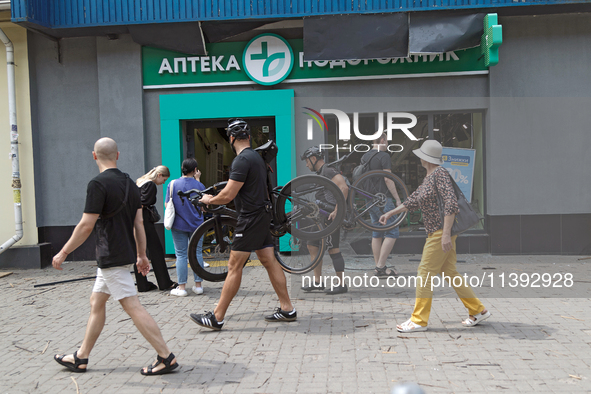 People are walking past a pharmacy with smashed windows near the Lukianivska metro station during a Russian missile attack in Kyiv, Ukraine,...