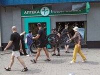 People are walking past a pharmacy with smashed windows near the Lukianivska metro station during a Russian missile attack in Kyiv, Ukraine,...