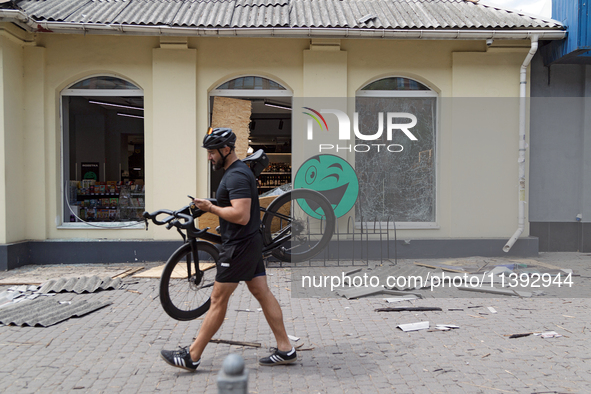 A man is carrying a bicycle past a shop near the Lukianivska metro station damaged during a Russian missile attack in Kyiv, Ukraine, on July...