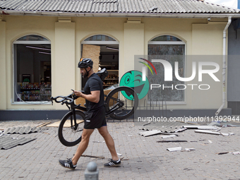 A man is carrying a bicycle past a shop near the Lukianivska metro station damaged during a Russian missile attack in Kyiv, Ukraine, on July...