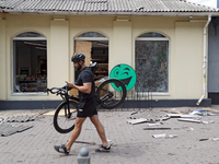 A man is carrying a bicycle past a shop near the Lukianivska metro station damaged during a Russian missile attack in Kyiv, Ukraine, on July...