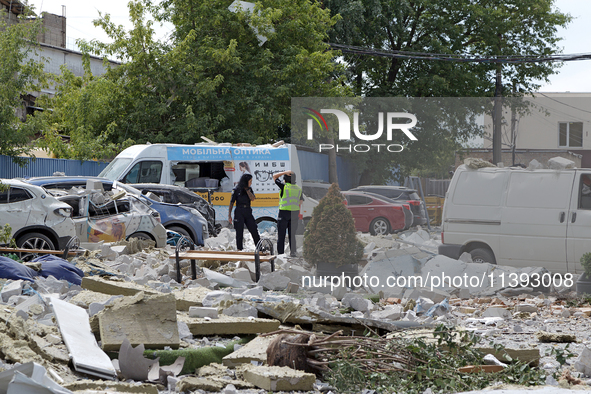 Police officers are standing among the rubble covering the ground at an office building in the Solomianskyi district damaged by a Russian mi...