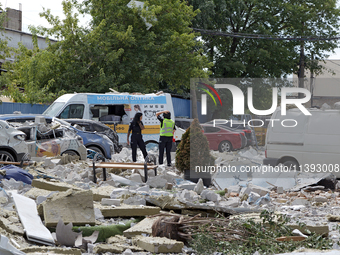 Police officers are standing among the rubble covering the ground at an office building in the Solomianskyi district damaged by a Russian mi...