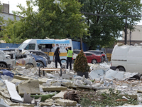 Police officers are standing among the rubble covering the ground at an office building in the Solomianskyi district damaged by a Russian mi...