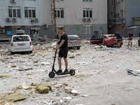 A man is riding an electric scooter past an office building damaged by a Russian missile strike in the Solomianskyi district in Kyiv, Ukrain...