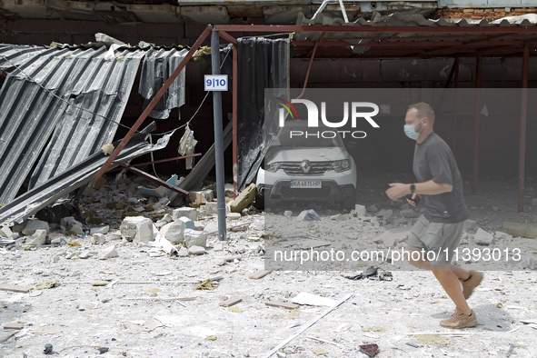 A man in a face mask is running past garages in the Solomianskyi district damaged by a Russian missile strike in Kyiv, Ukraine, on July 8, 2...