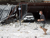 A man in a face mask is running past garages in the Solomianskyi district damaged by a Russian missile strike in Kyiv, Ukraine, on July 8, 2...