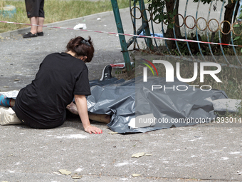 A woman is sitting on the ground by a man killed by a Russian missile strike in the Solomianskyi district in Kyiv, Ukraine, on July 8, 2024....