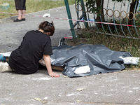 A woman is sitting on the ground by a man killed by a Russian missile strike in the Solomianskyi district in Kyiv, Ukraine, on July 8, 2024....