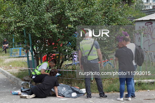 A woman is sitting on the ground by a man killed by a Russian missile strike in the Solomianskyi district in Kyiv, Ukraine, on July 8, 2024....