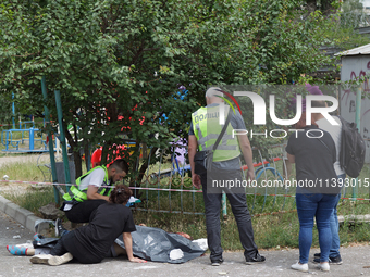 A woman is sitting on the ground by a man killed by a Russian missile strike in the Solomianskyi district in Kyiv, Ukraine, on July 8, 2024....