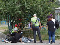 A woman is sitting on the ground by a man killed by a Russian missile strike in the Solomianskyi district in Kyiv, Ukraine, on July 8, 2024....