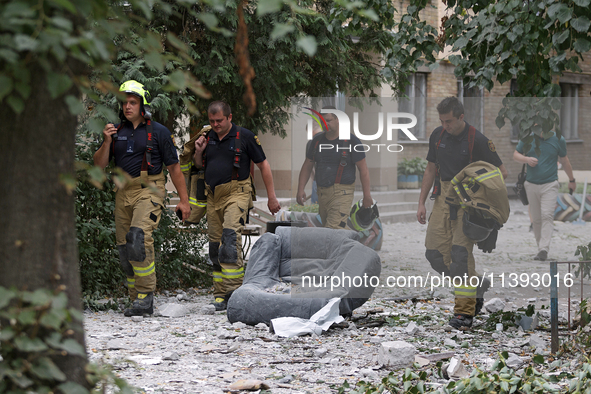 Rescue workers are walking past an armchair during a response effort to a Russian missile strike in the Solomianskyi district in Kyiv, Ukrai...