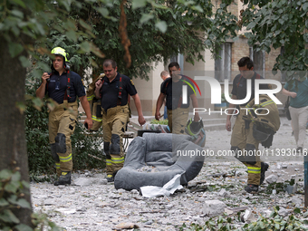 Rescue workers are walking past an armchair during a response effort to a Russian missile strike in the Solomianskyi district in Kyiv, Ukrai...