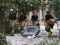 Rescue workers are walking past an armchair during a response effort to a Russian missile strike in the Solomianskyi district in Kyiv, Ukrai...