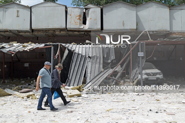 Two men are walking past garages in the Solomianskyi district damaged by a Russian missile strike in Kyiv, Ukraine, on July 8, 2024. NO USE...