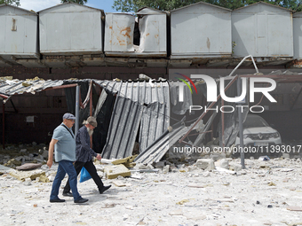 Two men are walking past garages in the Solomianskyi district damaged by a Russian missile strike in Kyiv, Ukraine, on July 8, 2024. NO USE...