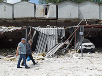 Two men are walking past garages in the Solomianskyi district damaged by a Russian missile strike in Kyiv, Ukraine, on July 8, 2024. NO USE...