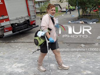 A woman is walking with a crutch in the Solomianskyi district during a response effort to a Russian missile strike in Kyiv, Ukraine, on July...