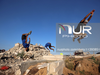 Palestinian youths are playing parkour at the ruins of a building destroyed in recent Israeli air strikes, in Zawayda, in the central Gaza S...