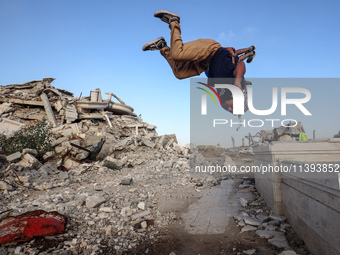 Palestinian youths are playing parkour at the ruins of a building destroyed in recent Israeli air strikes, in Zawayda, in the central Gaza S...