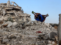 Palestinian youths are playing parkour at the ruins of a building destroyed in recent Israeli air strikes, in Zawayda, in the central Gaza S...