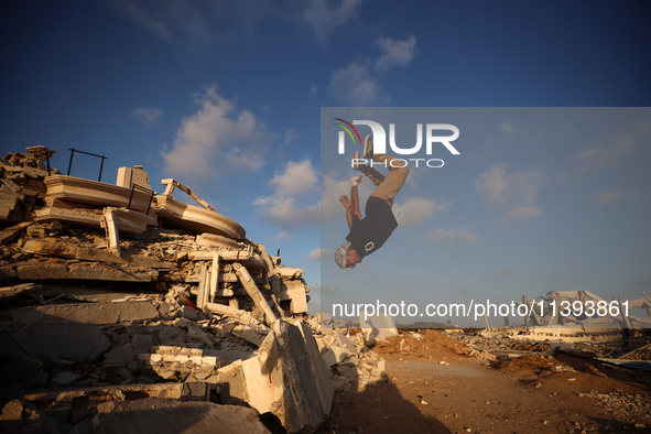 A Palestinian youth is practicing parkour at the ruins of a building destroyed in recent Israeli air strikes, in Zawayda in the central Gaza...