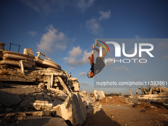 A Palestinian youth is practicing parkour at the ruins of a building destroyed in recent Israeli air strikes, in Zawayda in the central Gaza...