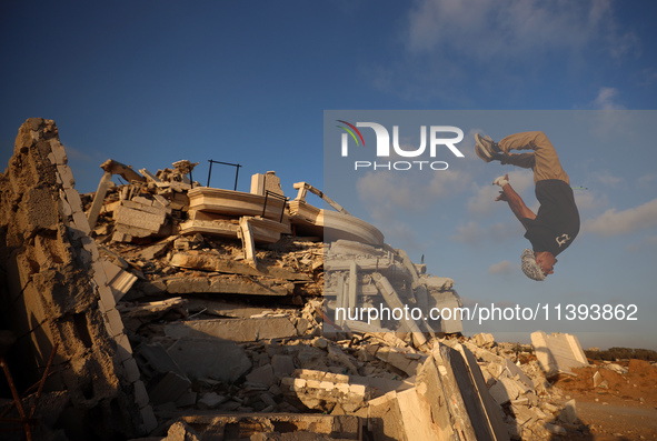 A Palestinian youth is practicing parkour at the ruins of a building destroyed in recent Israeli air strikes, in Zawayda in the central Gaza...