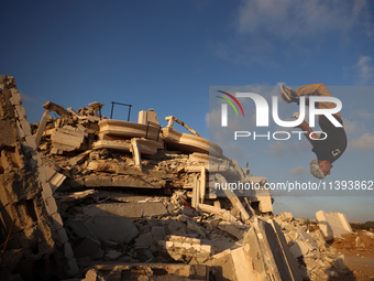 A Palestinian youth is practicing parkour at the ruins of a building destroyed in recent Israeli air strikes, in Zawayda in the central Gaza...